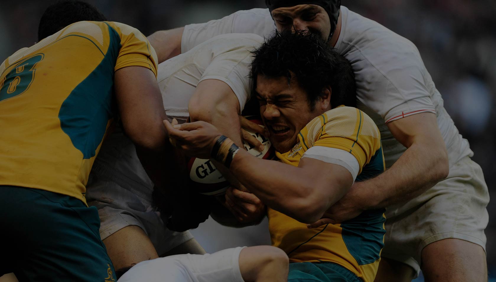 Australia's Digby Ioane holds onto the ball despite being aggressively tackled by two England players during an international match at Twickenhamin 2009