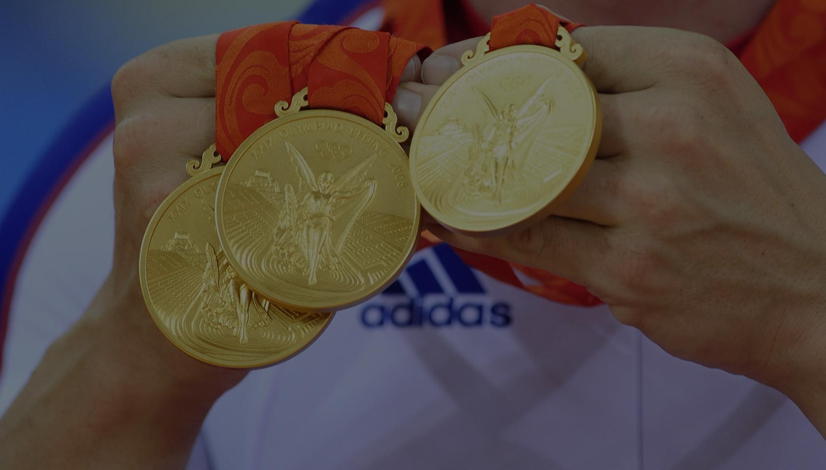 Chris Hoy shows off his three cycling gold medals at the Olympic Games in Beijing in 2008