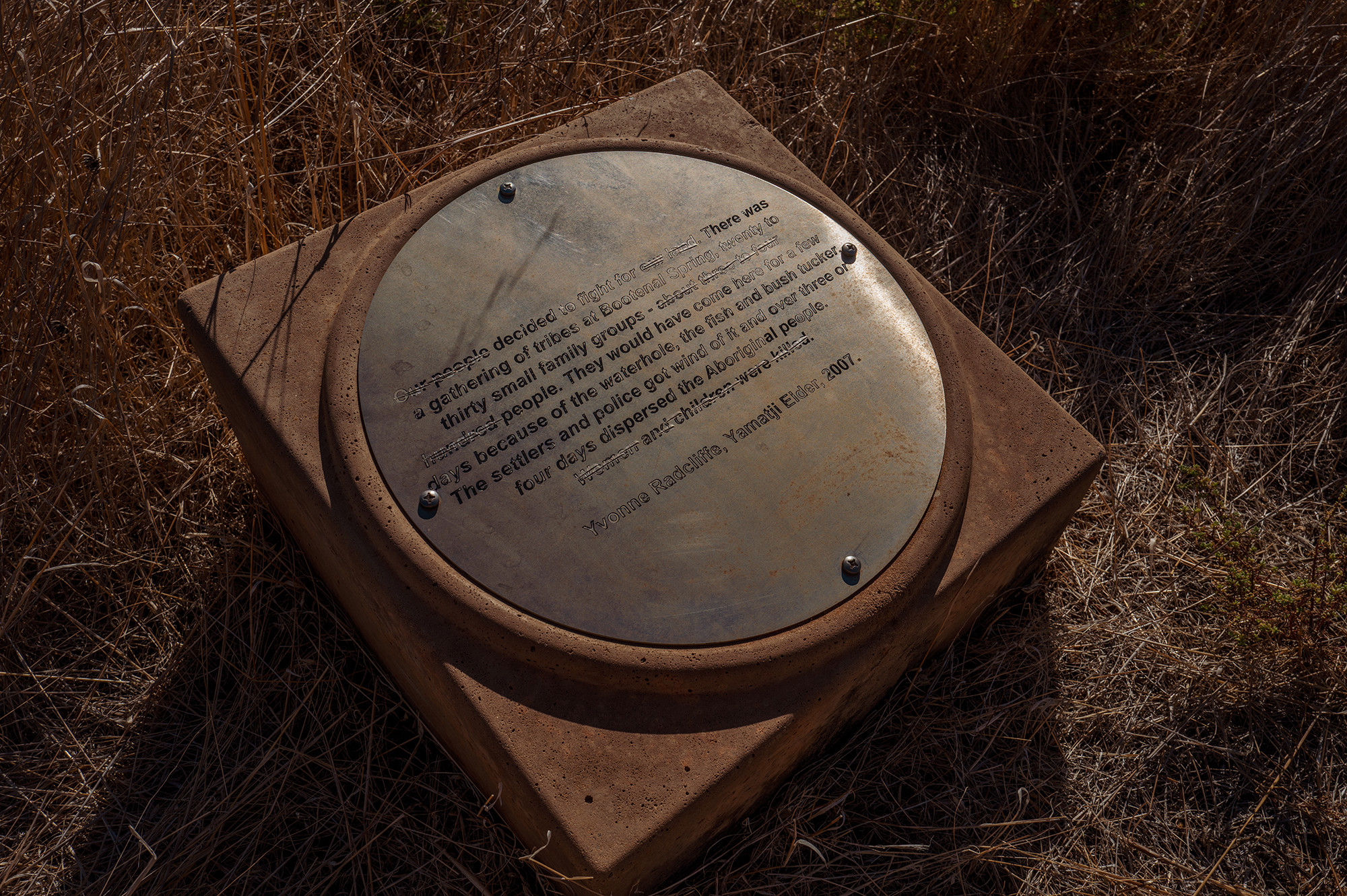 A plaque at the campground at Bootenal Springs, with scratch marks over some of the phrases describing the massacre there